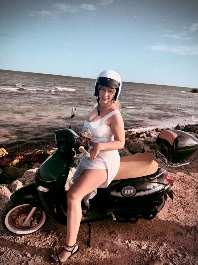 Rider with helmet on a scooter at sunset by the Tulum coast
